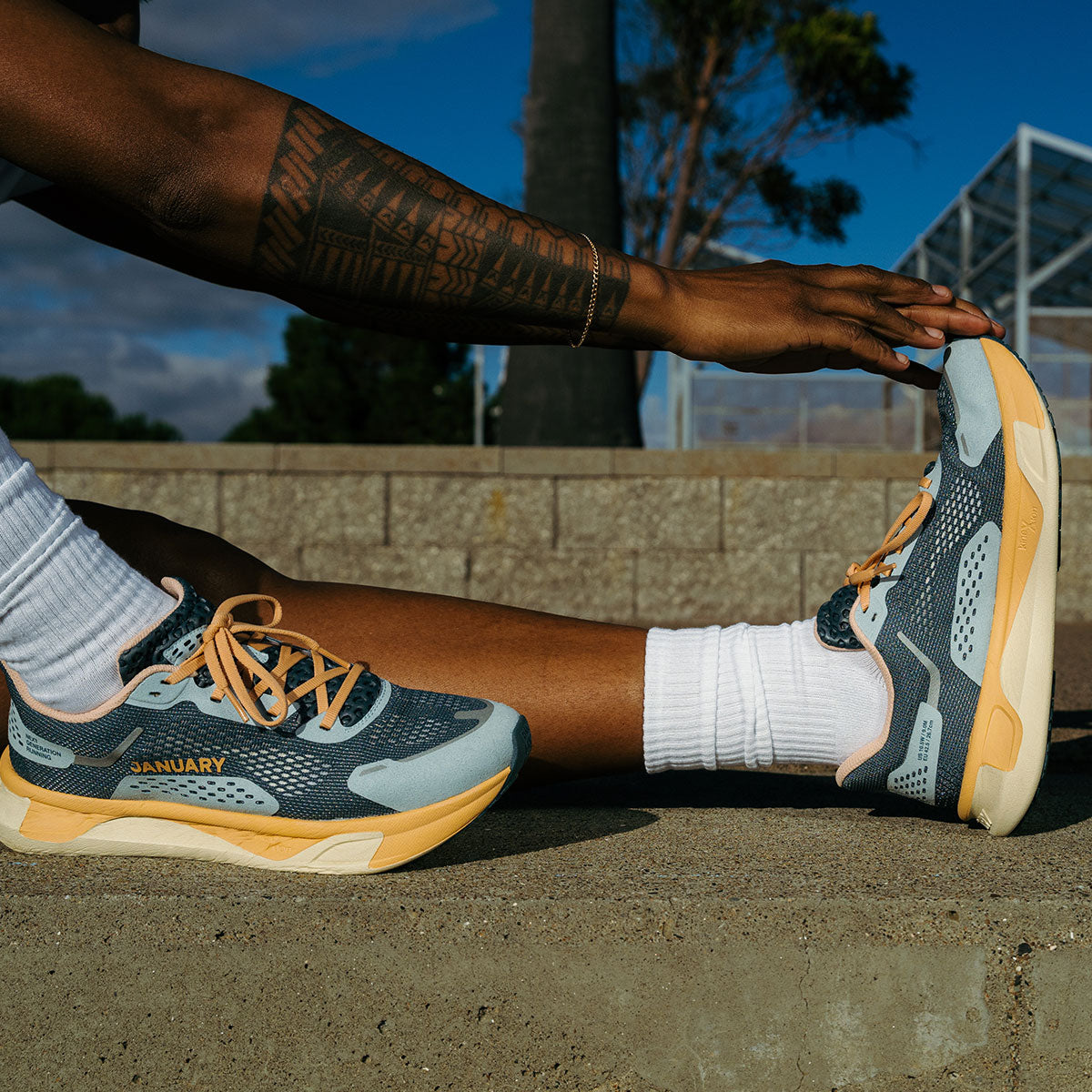 Person stretching legs wearing Twilight Fog shoe with 'January' branding, outdoors.